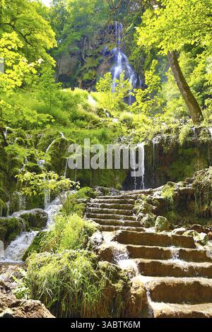 La cascata di Bad Urach, che si snoda su diversi gradini lungo una scogliera rocciosa, creando uno spruzzo sottile. La cascata è circondata da un verde denso Foto Stock
