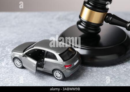 Legge sugli incidenti automobilistici. Modello di martelletto e auto su sfondo grigio Foto Stock