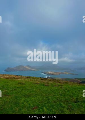 Le scogliere e la costa dell'Atlantico irlandese con onde che si infrangono, campi verdi e cieli lunari lungo la Wild Atlantic Way. Foto Stock