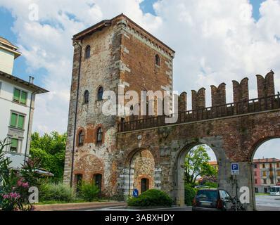 Porta Aquileia nelle mura di Udine, Italia. C15th. torre medievale in pietra con finestre ad arco gotiche, porta ad arco, muro di collegamento merlato Foto Stock