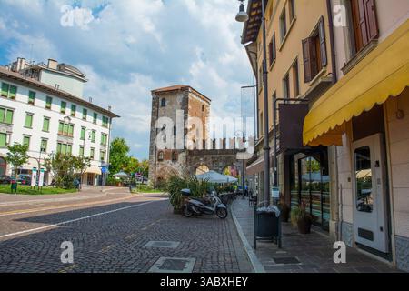 Porta Aquileia nelle mura di Udine, Italia. C15th. torre medievale in pietra con finestre ad arco gotiche, porta ad arco, muro di collegamento merlato Foto Stock