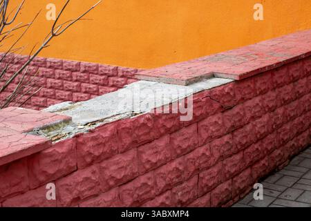 E' presente una parete di mattoni rosa caratterizzata da una sporgenza bianca posizionata lungo un lato di essa, che crea un interessante contrasto di colori Foto Stock