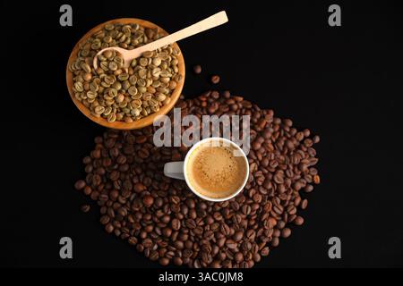 Tazza di caffè calda circondata da chicchi di caffè verdi e tostati, evidenziando il processo dal chicco grezzo alla bevanda preparata Foto Stock