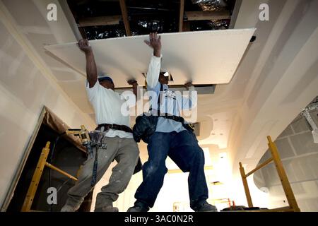 (PUBBLICATO il 03/03/2005, NC-1; NI-1) Jose Mun(accento sopra n)oz, sinistra, e Allen Mahan, destra, appendiabiti per cartongesso per sistemi avanzati a San Diego, preparatevi a installare un pezzo tagliato di cartongesso sul soffitto del nuovo edificio multiuso presso del Mar Hills Academy. La scuola, che è l'accademia delle arti del distretto, è l'ultima scuola a ottenere un auditorum per le esibizioni.--Laura Embry/Union-Tribune Foto Stock