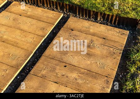 Lastre di pietra che ricordano tavole di legno sulla terrazza, che posano il pavimento sotto il pergolato nel giardino, costruiscono una veranda con giardino Foto Stock
