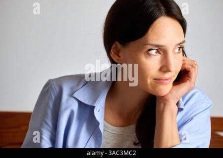 donna di 35 anni a casa, che pensa e guarda di lato Foto Stock