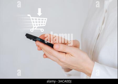 Donna con smartphone che visualizza un'interfaccia di un negozio online, che rappresenta l'e-commerce Foto Stock
