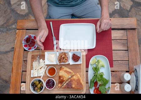 Colazione tradizionale turca con pane fresco, olive, formaggio, pomodori, cetrioli, e varietà di inceppamenti e spalmazioni. Godibile in un ambiente vivace, catturando l'essenza della cultura mattutina turca. Foto Stock