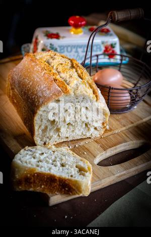 Pane appena fatto. Pane fresco a lievitazione naturale con crosta dorata su tagliere in legno Foto Stock