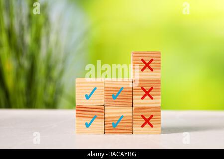 Approvazione del rifiuto. Cubi di legno con segni a croce e a scacchi sul tavolo Foto Stock