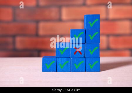 Approvazione del rifiuto. Cubi di legno con segni a croce e a scacchi sul tavolo Foto Stock