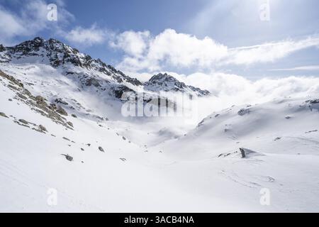 Nuvole suggestive in un paesaggio montano ventoso, salita a porta d'es-cha, tour sciistico Buendner Haute Route, Alpi Albula, Alpi Retiche, Grigioni, Easte Foto Stock