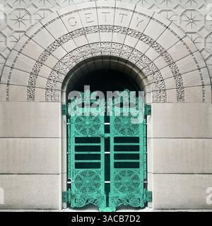 Ornato di bronzo verde la tomba di Getty, incorniciata da intricate incisioni in pietra e dal design ad arco romanico in uno storico cimitero di Chicago Foto Stock