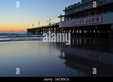 Il lungo molo di Daytona Beach in Florida si riflette nell'acqua dell'oceano all'alba sulla costa Foto Stock