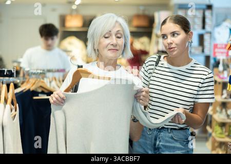 Due donne che scelgono un maglione comodo nel negozio di abbigliamento Foto Stock