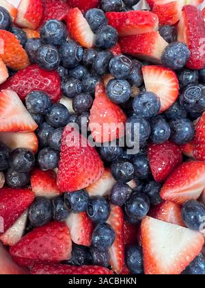 Fragole e mirtilli appena tagliate insieme per uno spuntino sano o un dessert Foto Stock