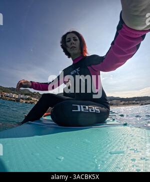 La donna seduta sul tabellone in piedi si accende su una action cam Foto Stock