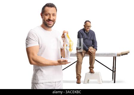 Paziente e chiropratico con un modello di osso del ginocchio isolato su sfondo bianco Foto Stock