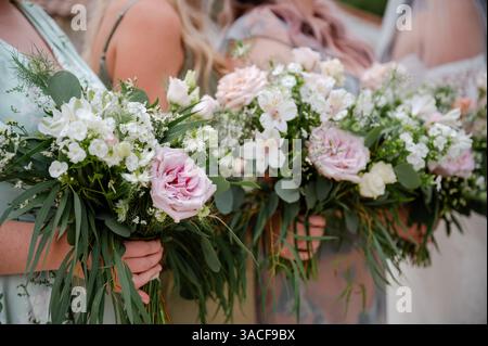 Damigelle d'onore con mazzi di rose e fiori selvatici bianchi e rosa Foto Stock