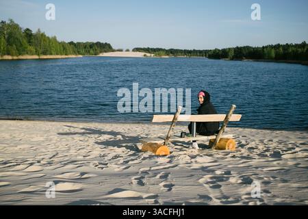 Momenti solitari su una panchina rustica che si affaccia su un lago tranquillo Foto Stock