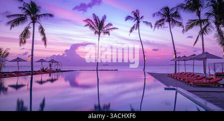 Il lussuoso tramonto sulla piscina a sfioro riflette i riflessi dell'hotel resort di fronte alla spiaggia in uno splendido paesaggio tropicale. Tranquilla vacanza al mare Foto Stock