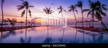 Il lussuoso tramonto sulla piscina a sfioro riflette i riflessi dell'hotel resort di fronte alla spiaggia in uno splendido paesaggio tropicale. Tranquilla vacanza al mare Foto Stock