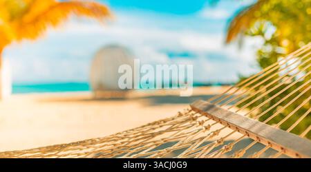 Ravvicinata serenità in spiaggia con amaca sotto foglie di palma sfocate. Perfette vacanze tropicali, relax costiero, rifugi assolati sul mare, vacanze estive Foto Stock