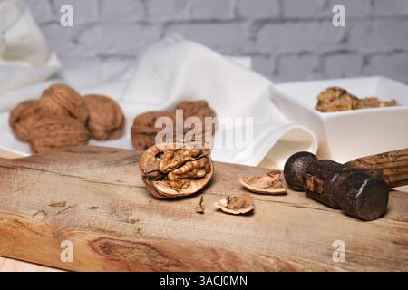Noce incrinato con martello su tagliere in legno. Foto Stock
