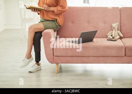 Ritratto ritagliato di una giovane donna moderna con disabilità che legge libro in minimi interni casa, spazio copia Foto Stock