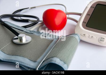 Vista laterale dello stetoscopio, a forma di cuore rosso e del misuratore della pressione sanguigna con spazio personalizzabile per il testo. Concetto medico e sanitario. Foto Stock