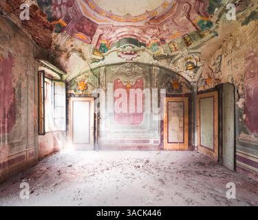 Interni decadenti di un edificio abbandonato con vernice sbucciata e finestre rotte, uno sguardo all'architettura urbana dimenticata. Foto Stock