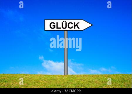 Il segno bianco su un prato verde punta nella direzione della felicità Foto Stock