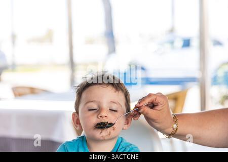 Il bambino che mangia riso nero con inchiostro di calamaro diventa disordinato Foto Stock