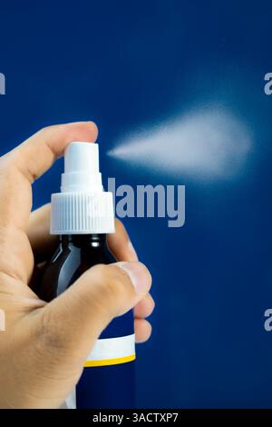 Modello di flacone spray per la crescita dei capelli con effetto nebulizzato, isolato su sfondo blu. Ideale per le vetrine dei prodotti. Foto Stock