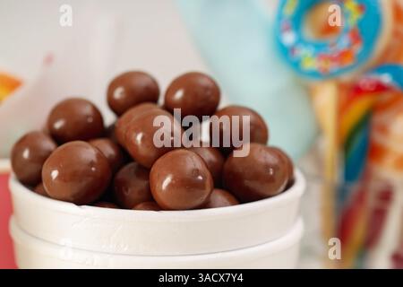 Caramelle. Dolci al cioccolato in tazza di carta su sfondo sfocato, primo piano Foto Stock