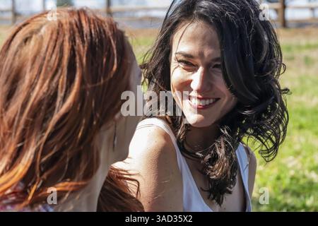 Due belle donne si godono un picnic primaverile all'aperto, circondato da fiori in fiore. Ridono e condividono i loro pensieri più profondi, il loro stretto legame evido Foto Stock
