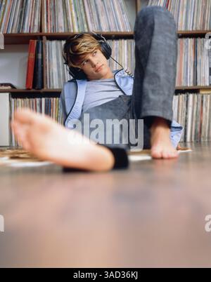 Giovane uomo che giace davanti alla collezione di dischi Foto Stock