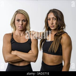 Due splendidi modelli Athletic FIT si mettono in posa con sicurezza, i loro muscoli tonificati sono evidenziati da un'illuminazione soffusa. Trasudano forza e grazia, mostrando la loro S. Foto Stock