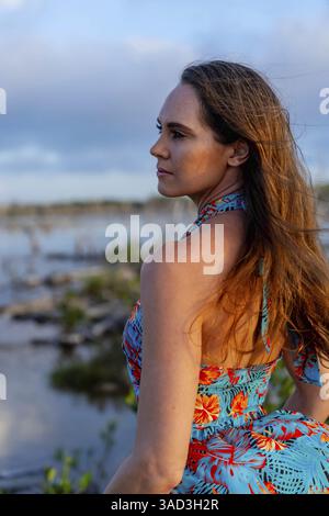 Nei vivaci tropici messicani, una donna stupenda si mette in posa in mezzo a una lussureggiante vegetazione mentre il sole dello Yucatan tramonta, gettando il suo bagliore dorato sulla canv della natura Foto Stock