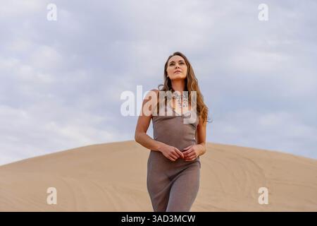 Il modello grazioso abbraccia la bellezza della natura tra le dune di sabbia, incarnando l'eleganza sullo sfondo di un vasto e naturale splendore, Jacumba, Stati Uniti Foto Stock