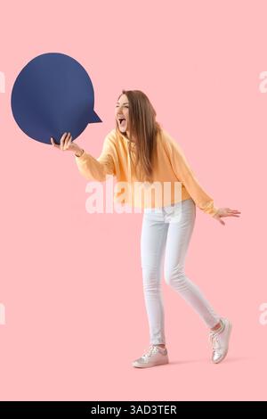 Giovane donna con bolla di linguaggio in bianco che grida su sfondo rosa Foto Stock