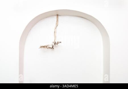 Vecchio cavo elettrico esposto a parete. Filo sbriciolato bianco in una nicchia ad arco. Concetto per fili abbandonati, incendi elettrici, pericoli per la sicurezza o. Foto Stock