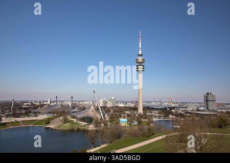 München, Deutschland 03. Aprile 2025: IM Bild: Blick vom Olympiaberg auf den Stadtpark mit Olympiastadion und SEE, dem Fernsehturm und rechts am Rand der BMW Zentrale mit dem Vierzylinder. Bayern *** Monaco di Baviera, Germania 03 aprile 2025 nella foto vista dall'Olympiaberg al parco cittadino con lo stadio olimpico e il lago, la torre della televisione e sulla destra ai margini della sede BMW con la Baviera a quattro cilindri Copyright: XFotostandx/xFritschx Foto Stock