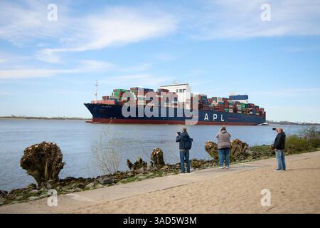 Amburgo, Germania. 5 aprile 2025. Gli escursionisti fotografano la nave portacontainer "APL Lion City", bandiera di Singapore, con il sole sulla spiaggia di Blankenese. Crediti: Georg Wendt/dpa/Alamy Live News Foto Stock