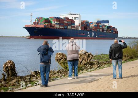 Amburgo, Germania. 5 aprile 2025. Gli escursionisti fotografano la nave portacontainer "APL Lion City", bandiera di Singapore, con il sole sulla spiaggia di Blankenese. Crediti: Georg Wendt/dpa/Alamy Live News Foto Stock