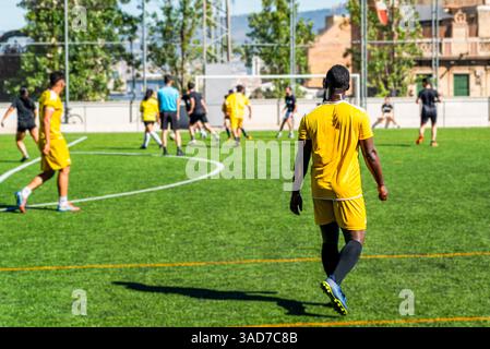 giovane afroamericano nero che gioca una partita in un campo da football in una giornata di sole con una squadra di corse miste. Giovane atleta che pratica il calcio facendo spor Foto Stock