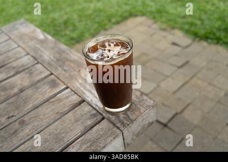 Caffè Ice americano in un bicchiere alto sopra il tavolo. Drink estivo freddo Foto Stock
