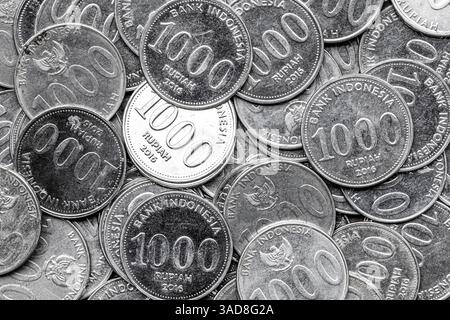 Mucchio di monete indonesiane da 1000 rupie. Vista inversa delle monete della Rupia indonesiana in primo piano Foto Stock