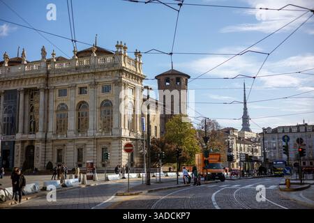 Torino, Italia - 08 novembre 2021: La facciata barocca di Palazzo Madama e la Torre del Tesoro si affacciano su una piazza della città con tram, traffico e pedoni Foto Stock