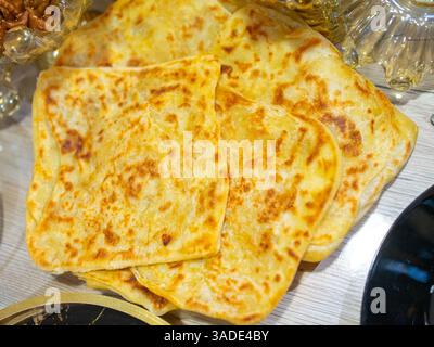 Deliziose focaccine dorate fresche dal forno, disposte ad arte su un tavolo di legno. Ideale per cene di gruppo, la loro consistenza croccante e. Foto Stock